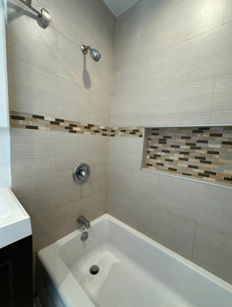 A white bathroom with a white tub and a shower head.